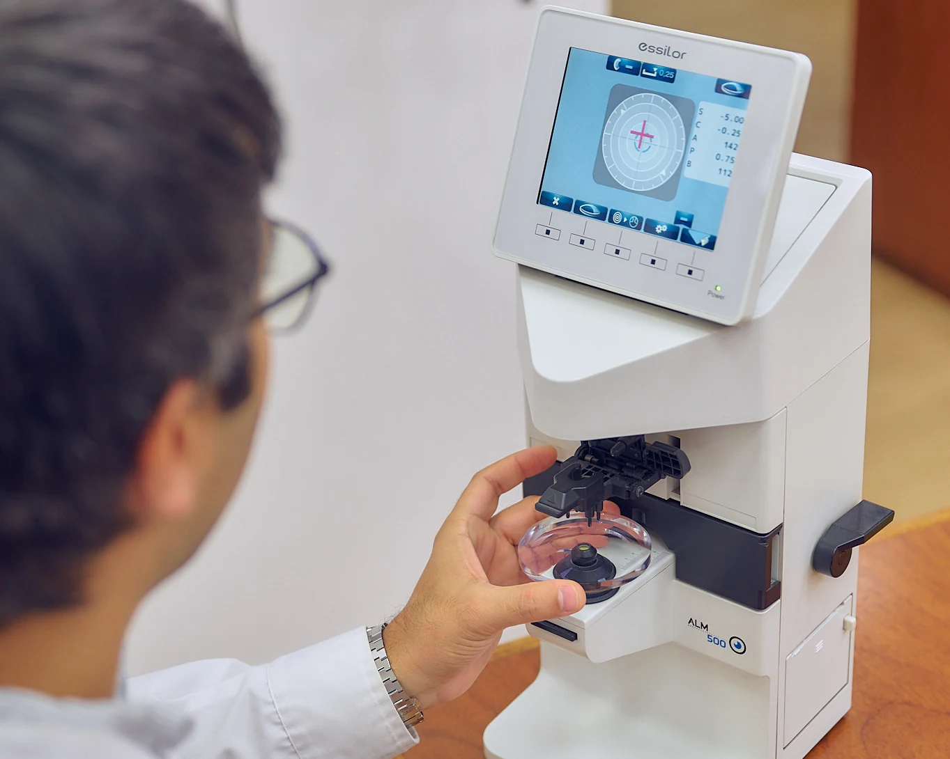 Un óptico de Palumbo coloca un cristal en el frontofocómetro para medir su graduación, en el local.